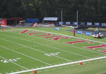 Football end zone painting bright red bright white grass field paint.