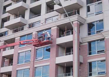 spray application of heat IR reflecting brick red concrete coating on apartment building.