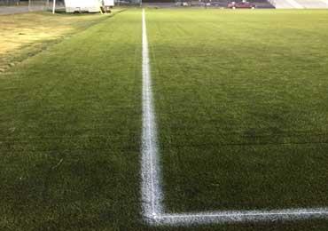 Paint permanent soccer field line of synthetic grass artificial turf athletic fields.