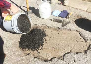 pour asphalt repair cold patch mix from the bucket into the pot hole.