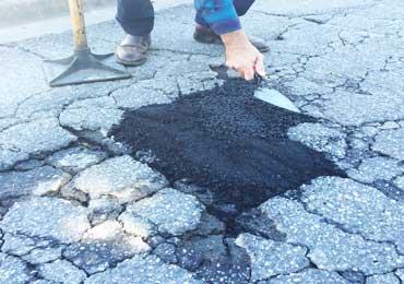 spread street road highway deck drive way pot hole repair using trowel.