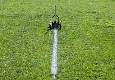Bright white lines football field with markers ground sockets paint machine.
