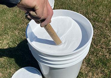 mixing athletic field striping white paint before spray application.