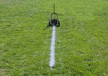 painting straight lines on football field on football fields using guide line string ground sockets.