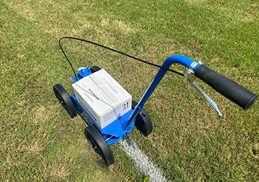 Painting white soccer field lines with aerosol spray cans.