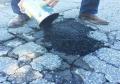 Pour asphalt repair fix material on pavement road spot to be reapired.