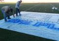 Aerosol chalk to paint removable logos on synthetic field turf.