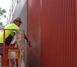 Worker Applying Lithium Concrete Coating On Red Industrial Wall