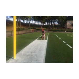 Spray application of white athletic field marking paint football endzone.